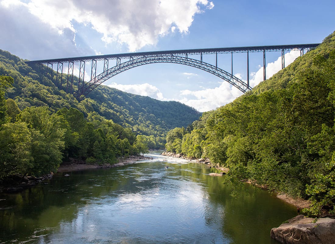 Logan, WV - Scenic View of a Railroad Bridge Across a River Surrounded by Green Trees in Logan West Virginia